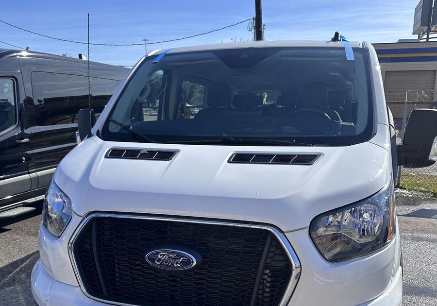 White Ford Transit passenger van with a new windshield