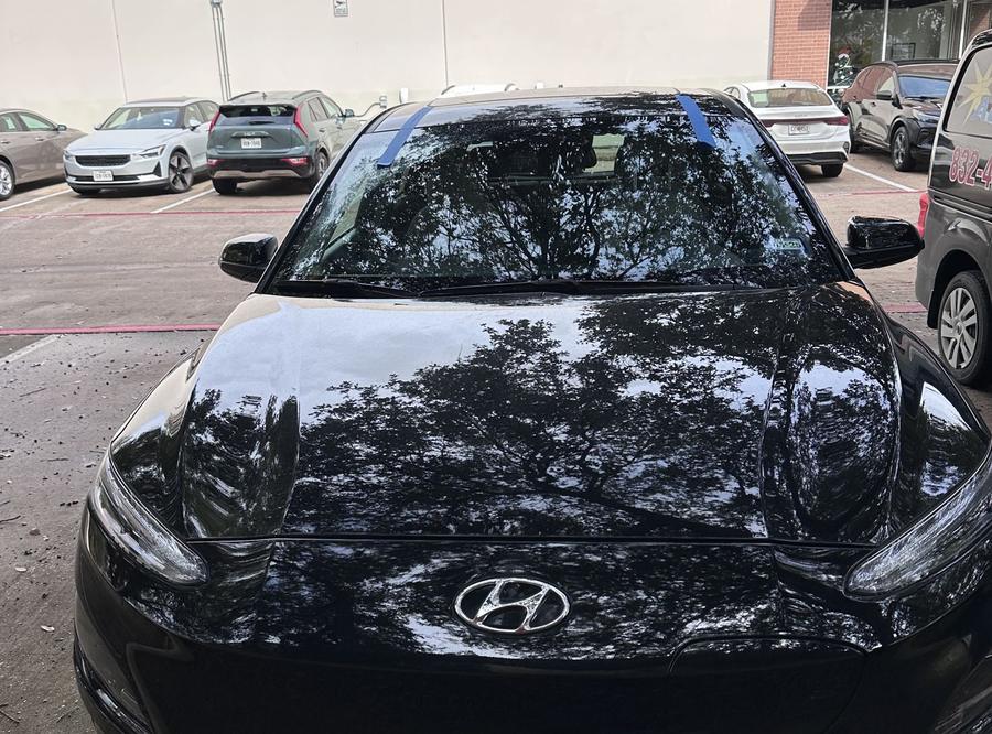 Black Hyundai Kona with a new windshield, taped while the adhesive sets
