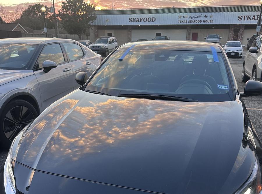 Black Nissan Altima with a freshly installed windshield at sunset