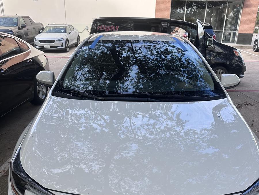 White Toyota Corolla with a new windshield, the Daylight van parked behind it
